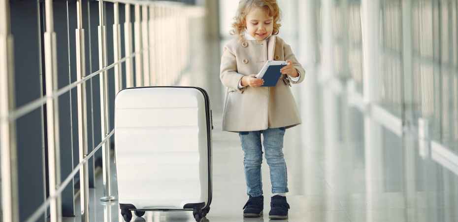 happy little girl with suitcase and passport in airport corridor