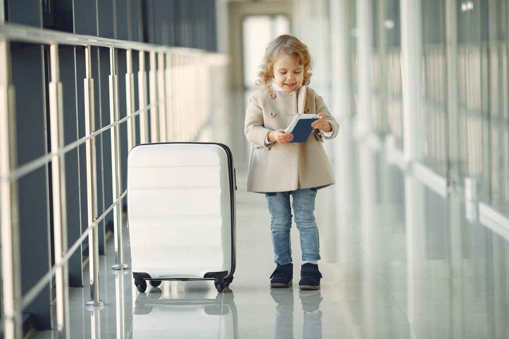 happy little girl with suitcase and passport in airport corridor
