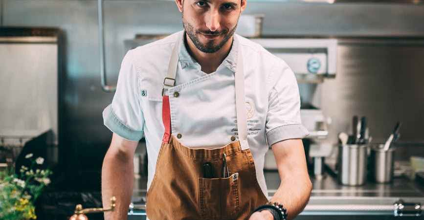 man in white chef uniform holding a brown wooden tray